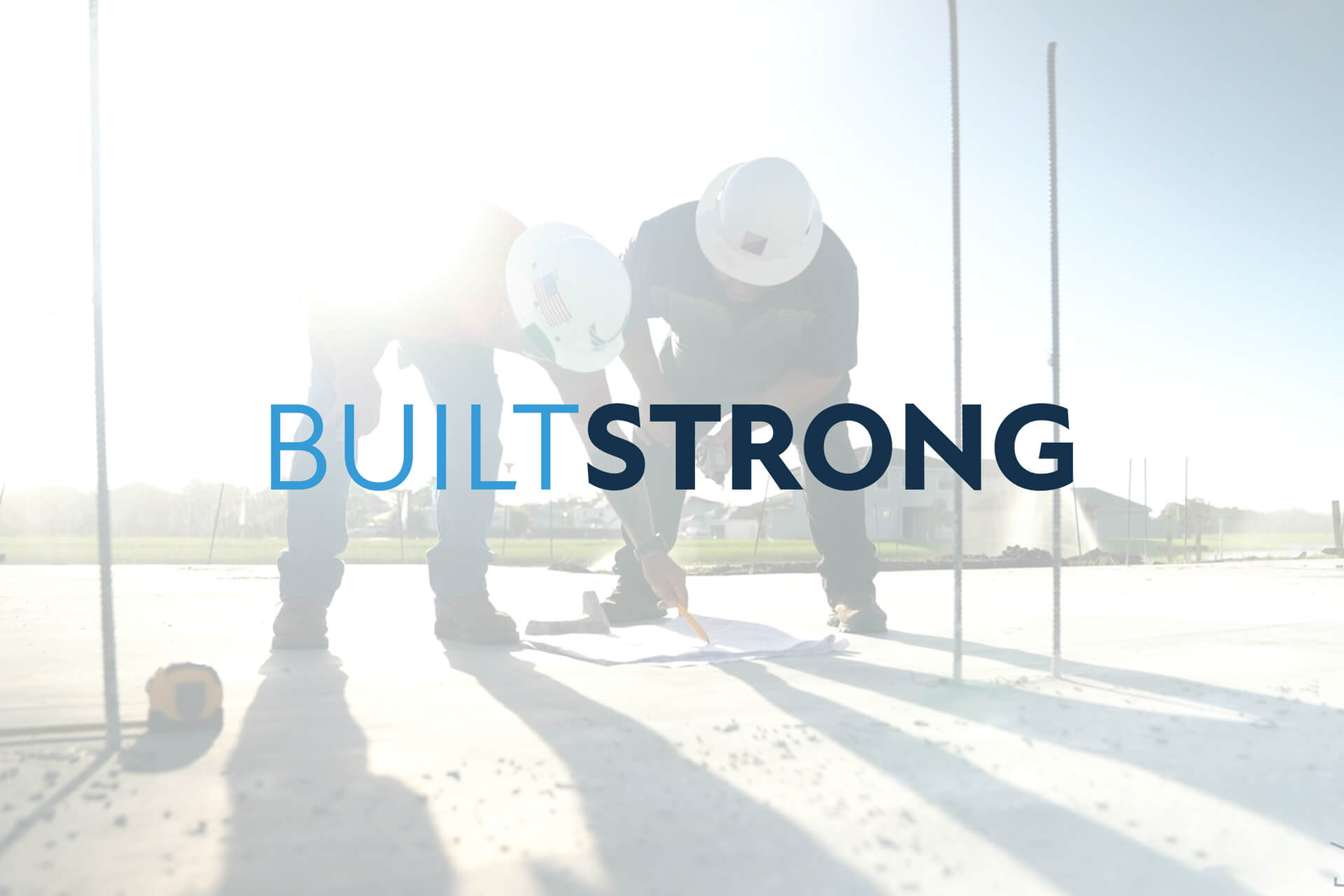 Two construction workers in safety helmets examine blueprints on a building site, with the sunlight casting silhouettes behind the text "BUILT STRONG." This commitment to quality is what defines Akel Homes' approach in crafting exceptional living spaces.