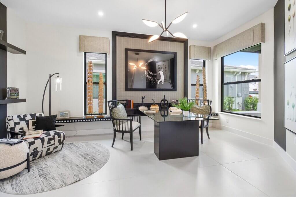 Modern home office with a glass desk, two black chairs, wall art, large windows, and neutral decor in a bright, tidy room—perfect for those seeking no CDD homes for sale in Palm Beach Gardens.