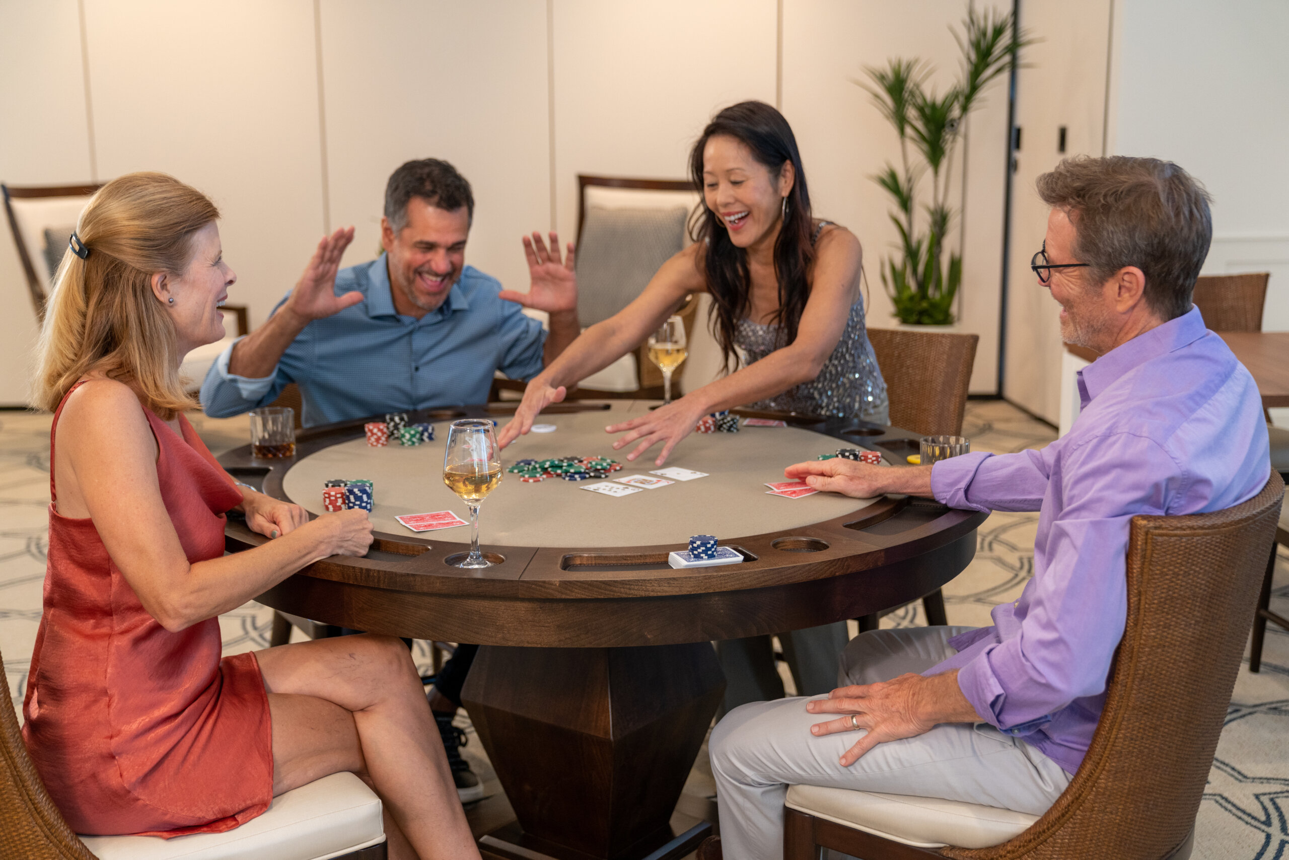 Four adults sit around a poker table, smiling and laughing as one woman reaches for chips. Playing cards, drinks, and laughter fill the air—imagine your days at Catalina Palms being this lively and fun.